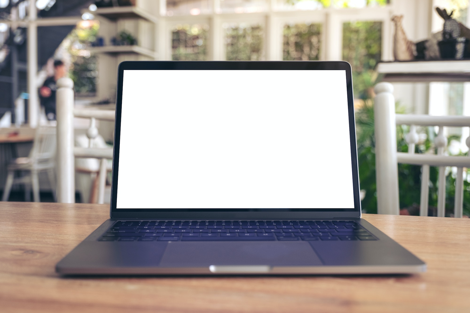 Mockup image of laptop with blank white desktop screen on wooden table